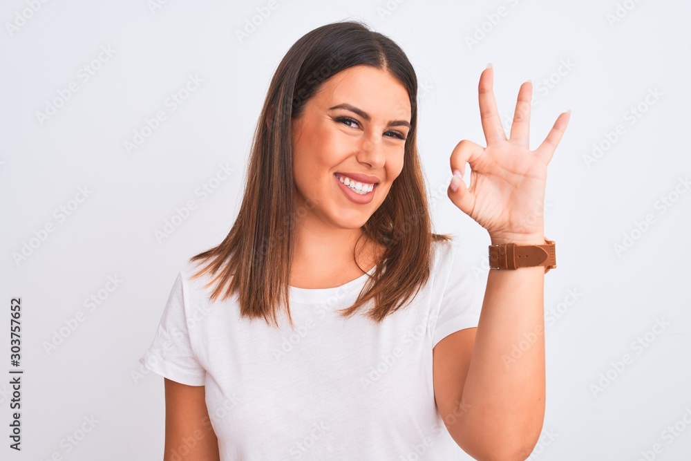 Portrait of beautiful and young brunette woman standing over isolated white background smiling positive doing ok sign with hand and fingers. Successful expression. Portrait of beautiful and young brunette woman standing over isolated white background smiling positive doing ok sign with hand and fingers. Successful expression.