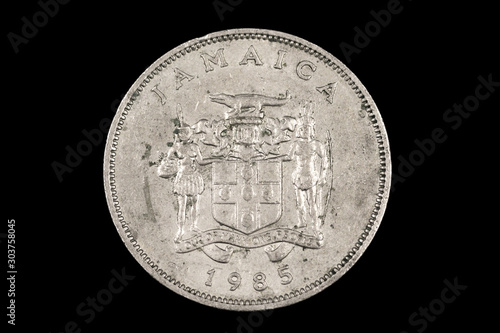 A close up, macro image of an old Jamaican twenty five cent coin isolated on a black background