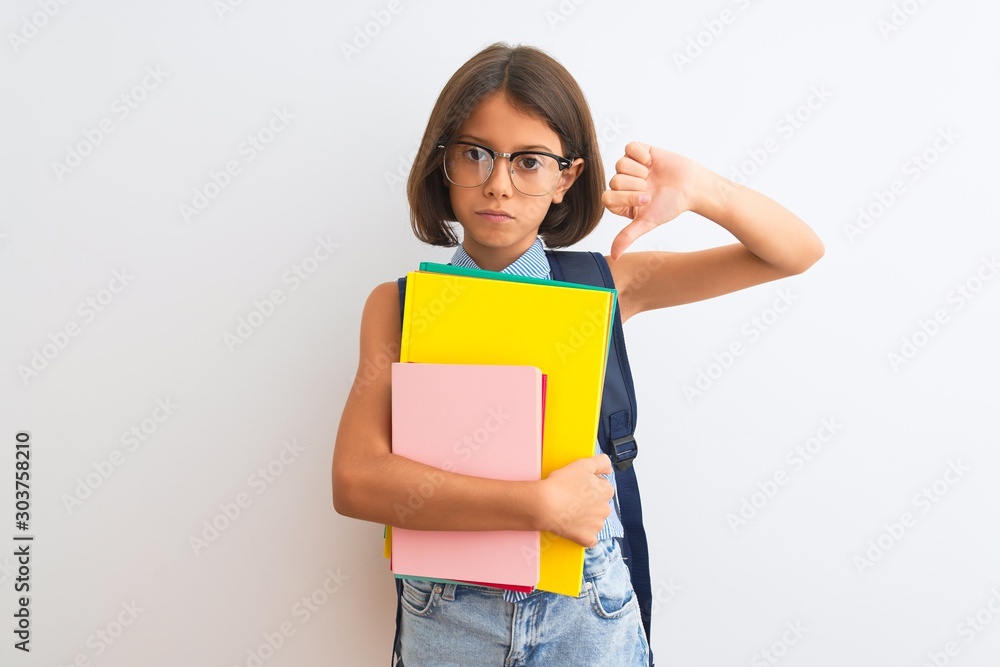 Beautiful student child girl wearing backpack glasses books over isolated white background with angry face, negative sign showing dislike with thumbs down, rejection concept Beautiful student child girl wearing backpack glasses books over isolated white background with angry face, negative sign showing dislike with thumbs down, rejection concept