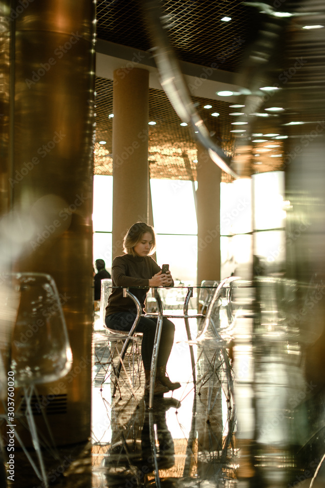 young european girl is chatting online by phone in a cafe mall young european girl is chatting online by phone in a cafe mall