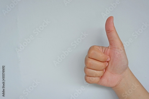 Female hand gesturing Ok sign on isolated on grey background. Side view close up details.