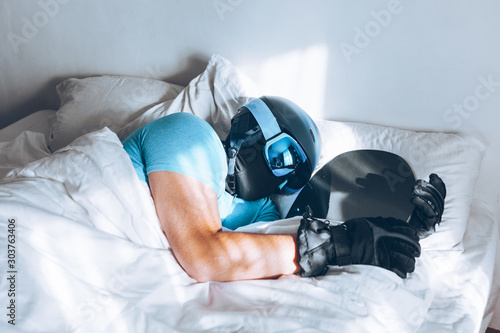 man in bed with snowboard ski googles and helmet