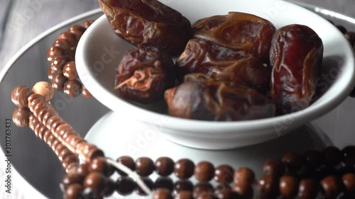 Islamic Concept: Cinematic shot of Tamar (dates) and Tasbih (rosary beads) on a rotating display. Dates usually are eaten during suhoor and iftar in Ramadhan photo