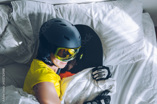 woman sleeping in bed with snowboard dreaming about ski at snow mountains
