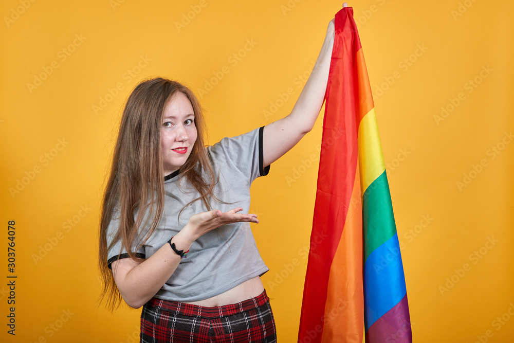Attractive stylish unshaven young woman in shirt posing isolated on white background studio portrait. People lifestyle concept, standing with outstretched hand showing on LGBT flag Attractive stylish unshaven young woman in shirt posing isolated on white background studio portrait. People lifestyle concept, standing with outstretched hand showing on LGBT flag