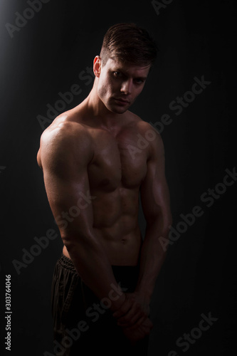 Muscular bodybuilder posing with a naked torso on a black background in the dark with backlight. Sexy man. © Михаил Гута