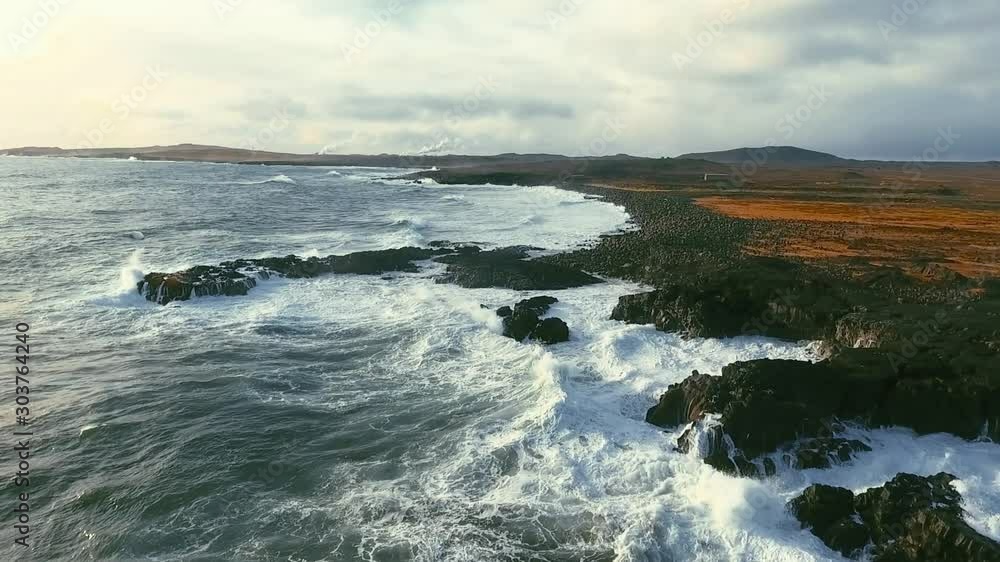 Powerful ocean waves crashing on the rocks in the western part of Iceland in the sunset light Powerful ocean waves crashing on the rocks in the western part of Iceland in the sunset light