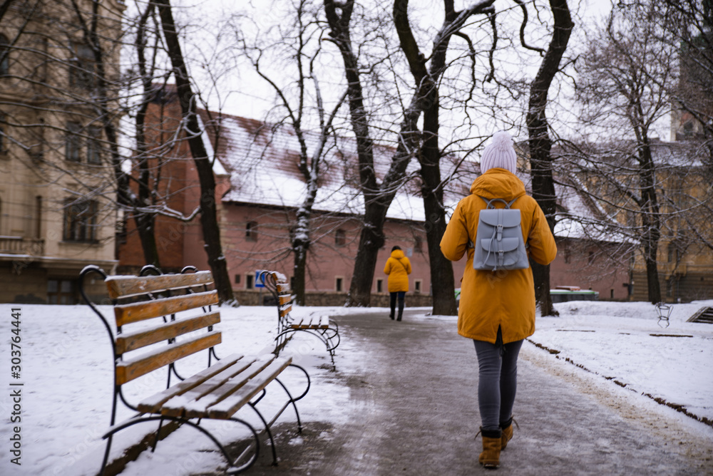 view from behind woman walking by snowed city street view from behind woman walking by snowed city street