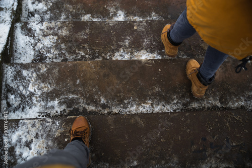 man and woman legs waking by icy slippery stairs