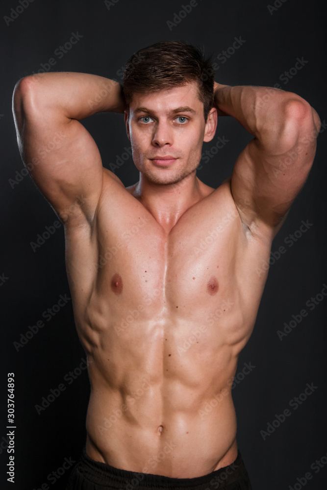 Bodybuilder holds muscular arms on head. Photo in studio on a black background. Bodybuilder holds muscular arms on head. Photo in studio on a black background.