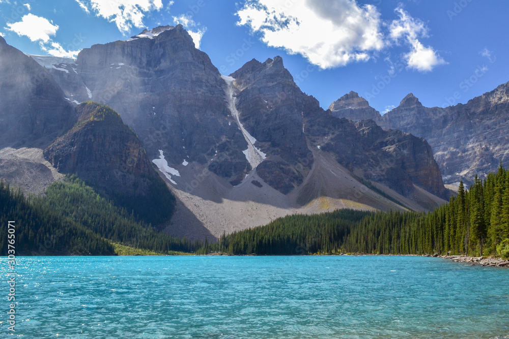 Iconic Canadian landscape, trip of a lifetime, Moraine Lake with it's glacier fed light blue turquoise waters and majestic peaks on a sunny day in the end of august, wilderness forest landscape.