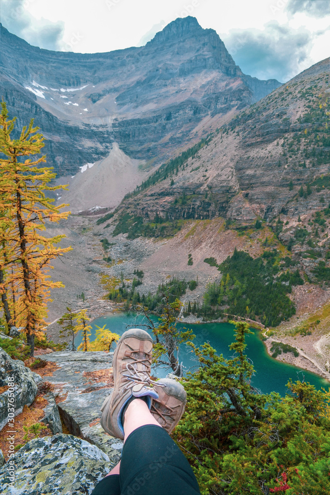 Φωτογραφία Tired hiker feet resting down on the top of the mountain summit overlooking Lake Agnes in Banff national Park, Alberta, view from Big Beehive