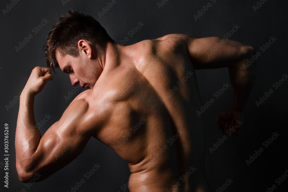 Muscular bodybuilder man posing on black background. View from the back. Muscular bodybuilder man posing on black background. View from the back.