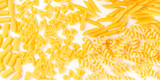 Italian pasta texture panorama, a flat lay banner, top shot on a white background. Fusilli, farfalle, penne, rigatoni