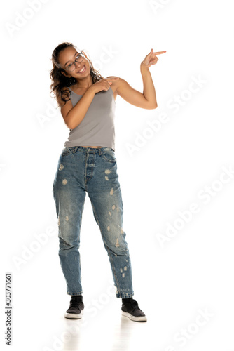 Young Indian woman in jeans standing on white background and pointing