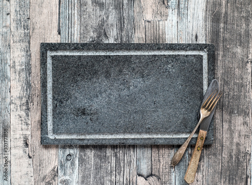 Gray Blackboard for your text, vintage fork and knife on a wooden table. Top view with copy space.