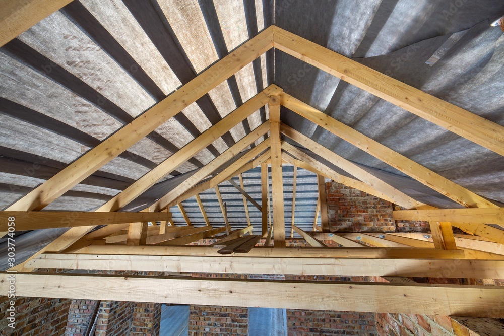 Φωτογραφία Attic of a building under construction with wooden beams of a roof structure and brick walls