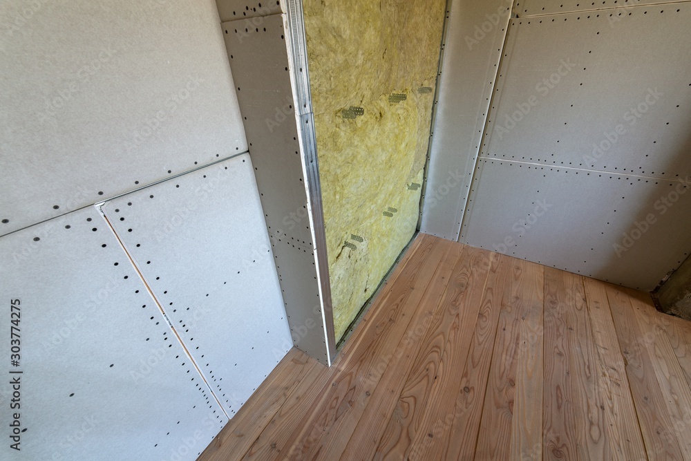 Wall of a room under renovation with mineral rock wool insulation and metal frame prepared for drywall plates. Wall of a room under renovation with mineral rock wool insulation and metal frame prepared for drywall plates.