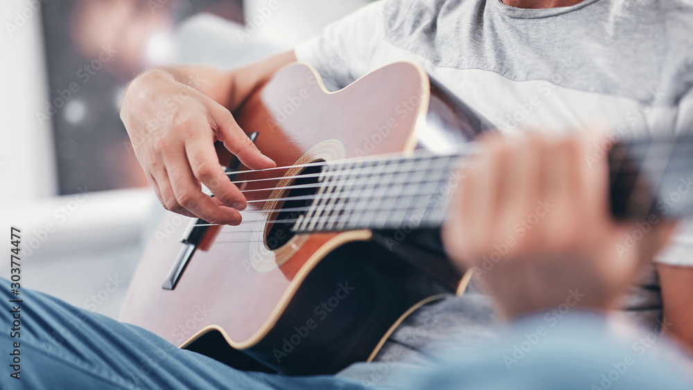 Fototapeta premium Man playing acoustic guitar in the living room.