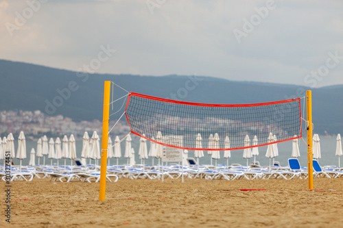 Empty volleyball net on a sandy beach on the sea shore in summer.