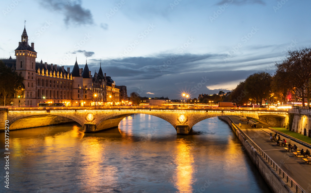 Stone bridge Pont au Change in Paris at the dusk. On the left are towers of Conciergerie, on right northern bank of river Seine