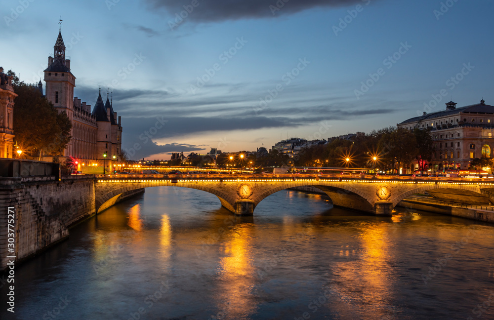 Stone bridge Pont au Change in Paris at the dusk. On the left are towers of Conciergerie, on right northern bank of river Seine