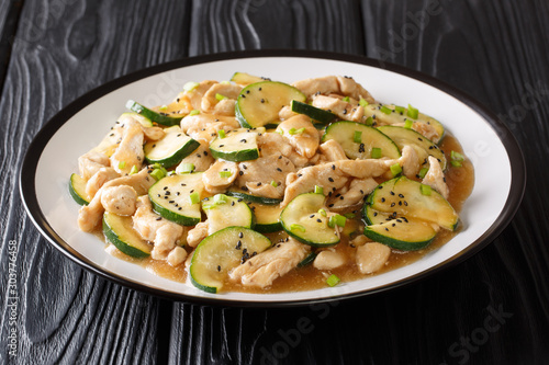 Serving of fried chicken breast with zucchini, sesame seeds and onions close-up on a plate. horizontal