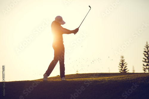 Golf swing on the course. Golfer performs a golf shot from the fairway. Sunny summer day. Concept: sport, relax, tourism, welfare.
