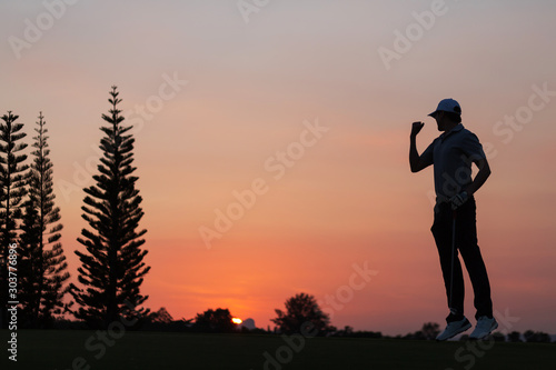 Sport Healthy. Golfing game. Asian man golfer action to win after long putting golf ball on the green golf, outdoors sunset time, space. Healthy Concept