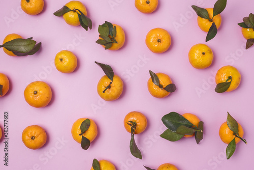 Ripe Fresh Tangerines or Citrus with Leaves on Pink background Pattern Top View