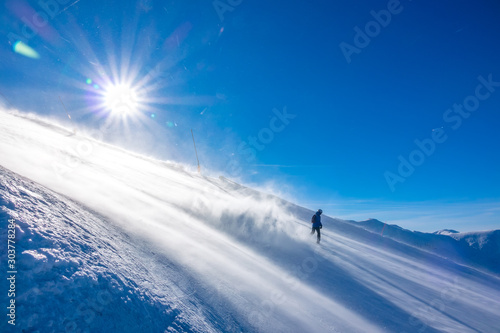 Snowboarder Raises a lot of Snow Dust in the Sun on a Steep Ski Slope