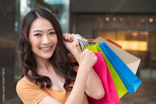 happy smiling woman shopping with colorful shopping bag in shopping mall showing thumb up; concept of buying, grand sale, boxing day, celebration sale, discount, good deal for woman shoppers