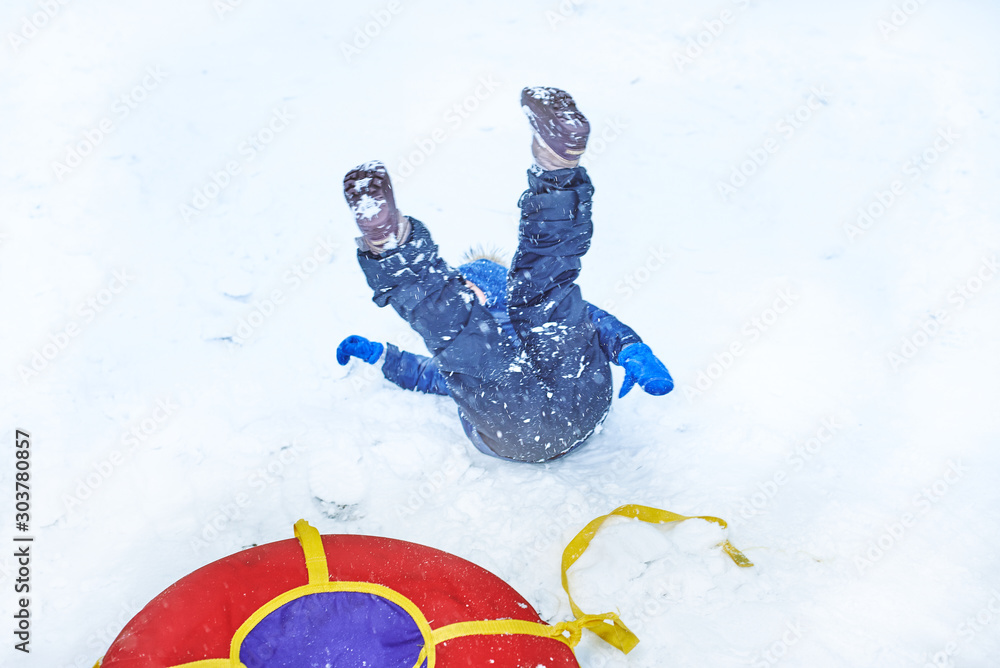 little boy in winter fell from sled tubing