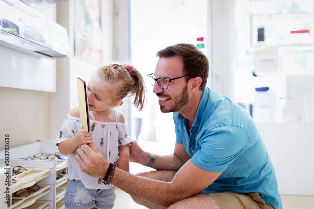Φωτογραφία Young man and his cute daughter are choosing the best apropriate eyeglasses in o