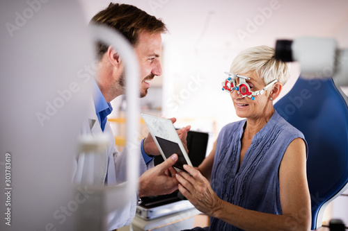 Optometrist examining senior woman in modern ophthalmology clinic