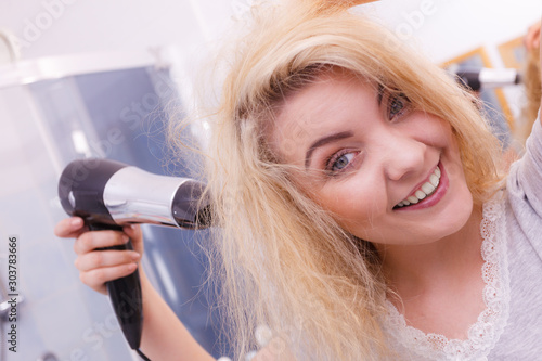Woman drying hair in bathroom