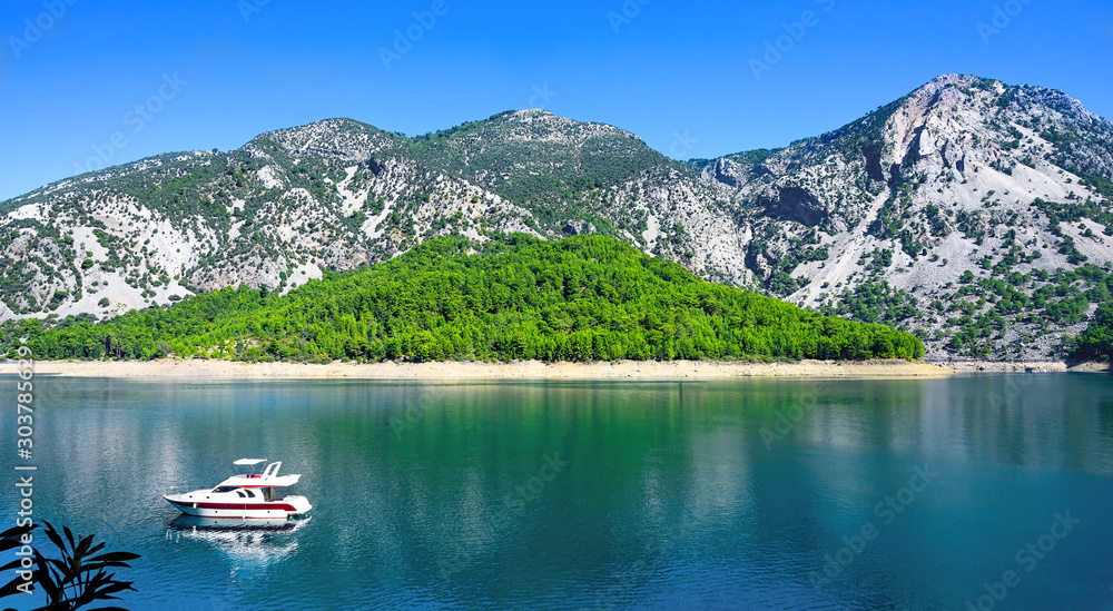 Beautiful mountain lake landscape with motor yacht.