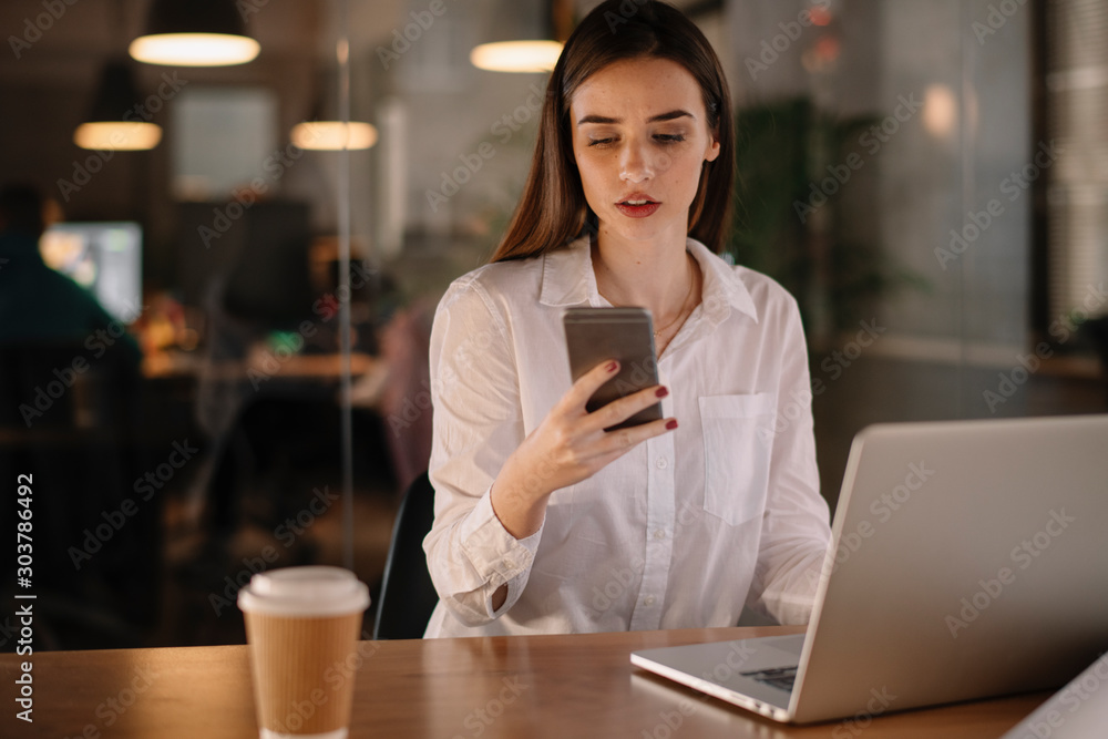Tired businesswoman using phone in office Tired businesswoman using phone in office
