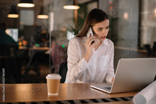 Tired businesswoman using phone in office