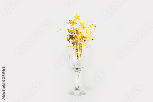 Confetti in the form of stars poured glasses of champagne on a white background. View from above.