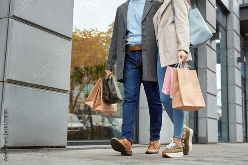 Adult woman and man walking together with shopping bags
