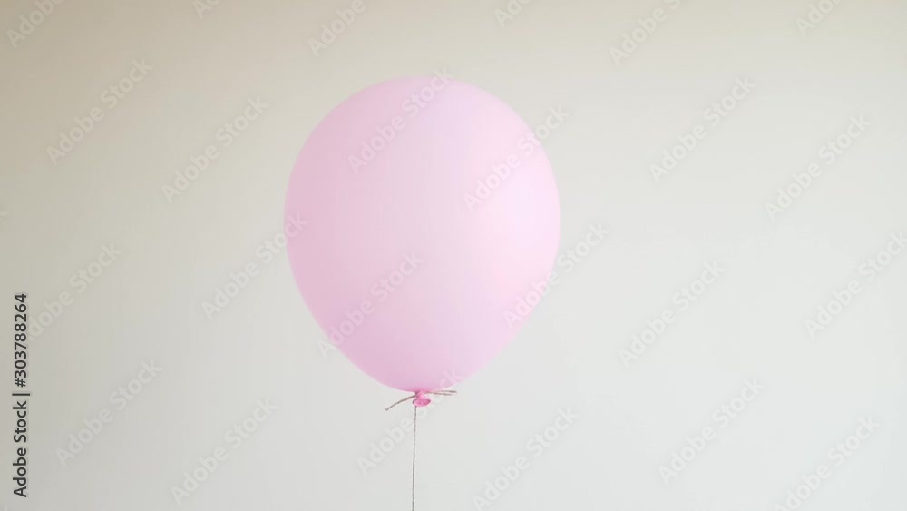 Light helium balloon in pink floating against off white wall, celebration, birthday concept Light helium balloon in pink floating against off white wall, celebration, birthday concept