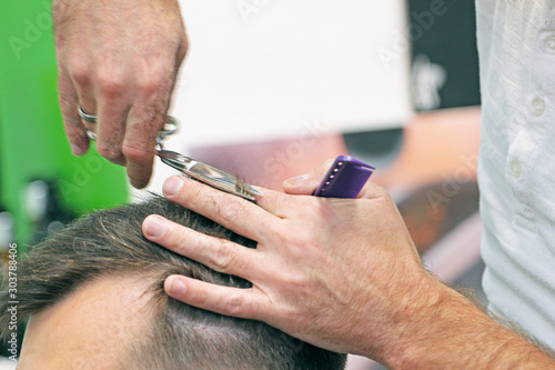 hairdresser cuts hair for boy with scissors and comb in barber shop, classic haircut