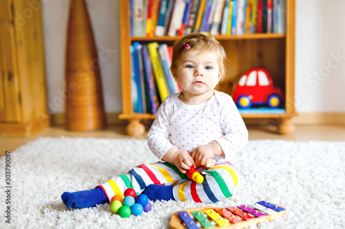 Adorable cute beautiful little baby girl playing with educational toys at home or nursery. Happy healthy child having fun with colorful music toy xylophone Kid learning different skills