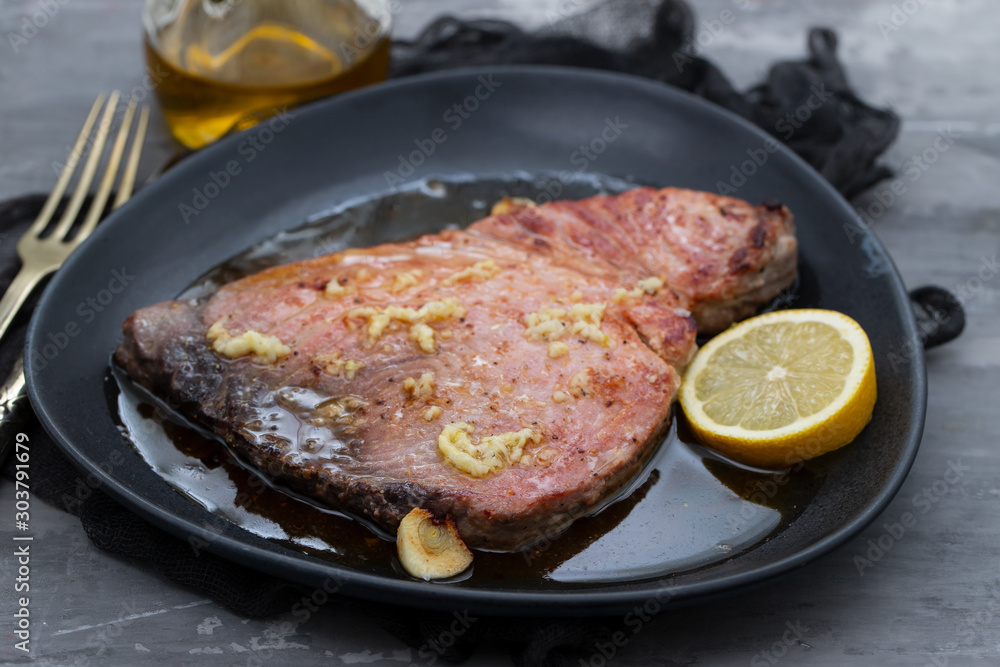 fried tuna with salt and lemon on dark plate fried tuna with salt and lemon on dark plate