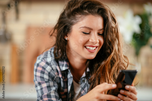 Young woman in kitchen. Beautiful woman using phone