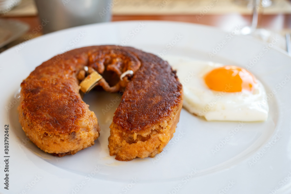 typical portuguese smoked sausage with fried egg on white plate typical portuguese smoked sausage with fried egg on white plate