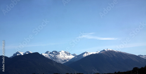 View over snow-covered mountain peak against blue sky © afrumgartz