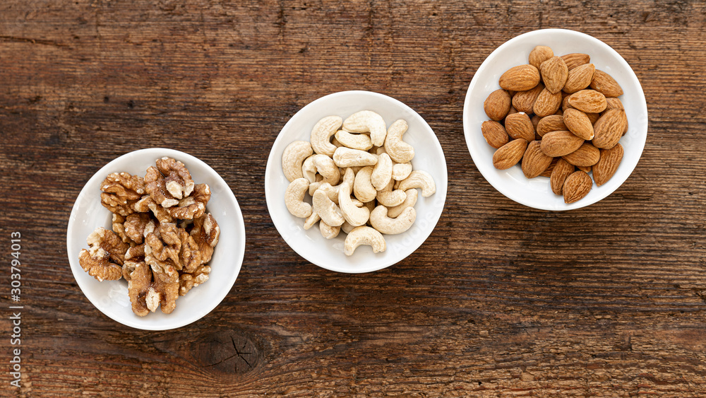 Walnüsse, Cashewkerne und Mandeln in Schüsseln auf altem Holz Walnüsse, Cashewkerne und Mandeln in Schüsseln auf altem Holz