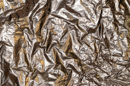 Silver foil background with shiny crumpled surface for textured background.